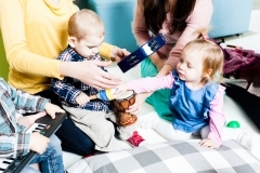 Toddlers playing instruments with two adults.