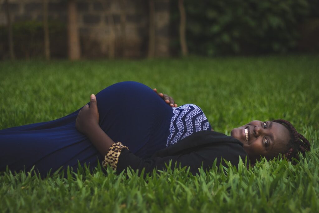 Femme enceinte noire allongée sur l'herbe.